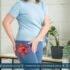 Middle-aged woman holding her hip in discomfort while walking indoors, indicating possible hip joint pain