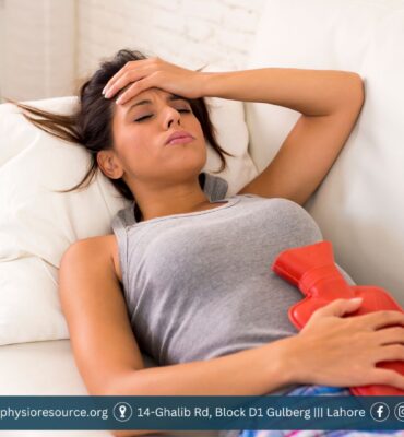 Young woman using a heating pad on her lower abdomen while resting on a couch to relieve menstrual cramps naturally