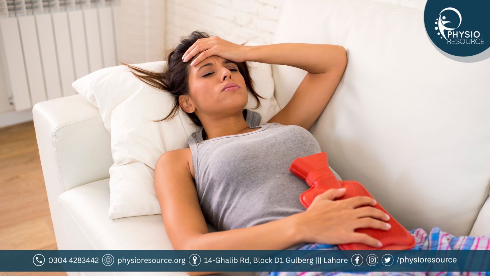 Young woman using a heating pad on her lower abdomen while resting on a couch to relieve menstrual cramps naturally