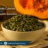 A bowl filled with green pumpkin seeds sits on a cloth napkin atop a wooden surface. A halved pumpkin is visible in the background. Image for PhysioResource.