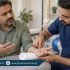 Male physiotherapist examining a patient’s palm and bent fingers while the wrist rests on a rolled towel.